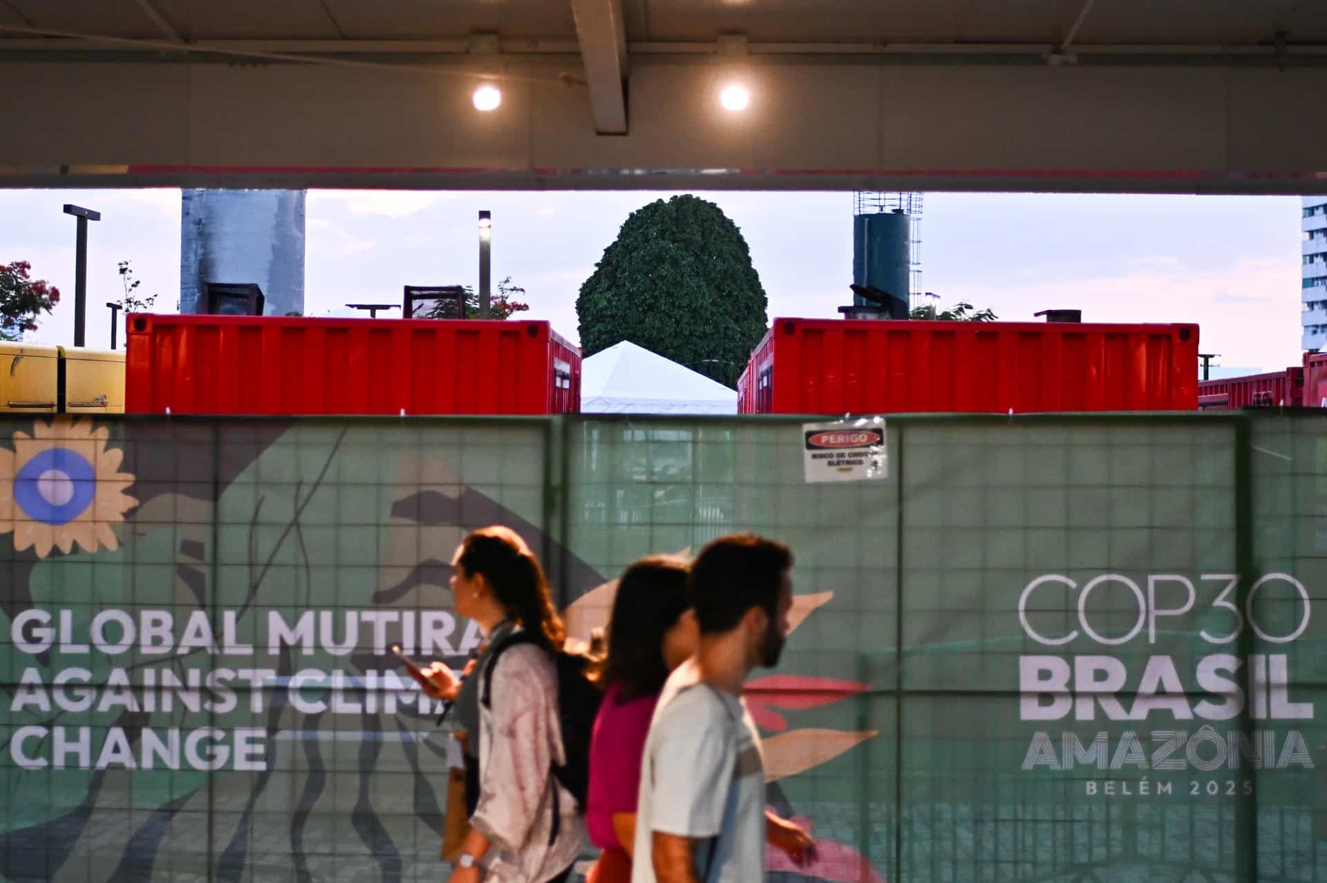 Personas caminan junto a generadores eléctricos que funcionan con diésel a las afueras del Centro de Convenciones Hangar donde se realiza la COP30, este lunes en Belém (Brasil). EFE/ Andre Borges