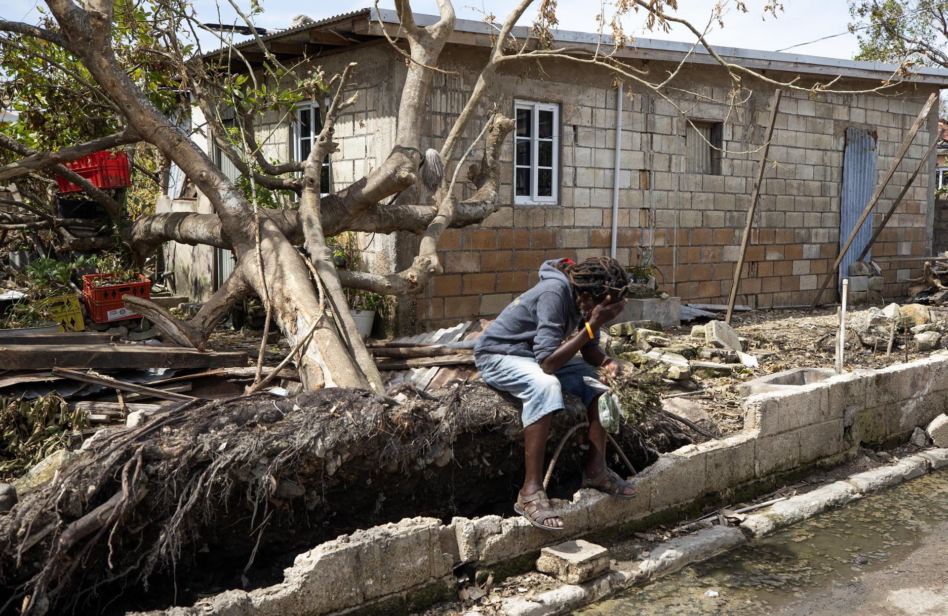 Un hombre descansa frente a una casa llena de escombros tras el paso del huracán Melissa en Falmouth (Jamaica). EFE/Orlando Barría