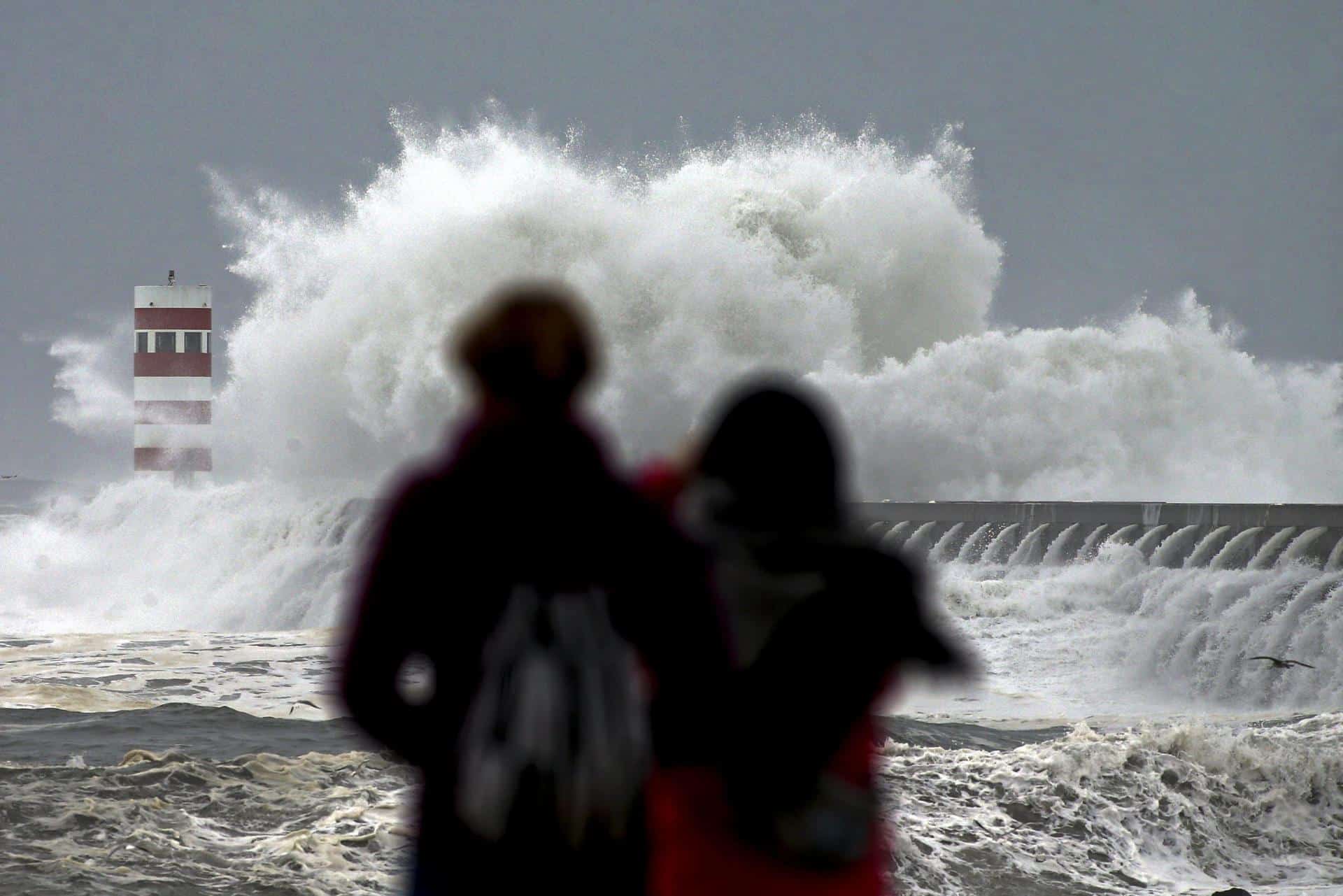 Dos personas observan las olas que chocan contra el faro de Cabedelo en Oporto en una imagen de archivo. EFE/Jose Coelho