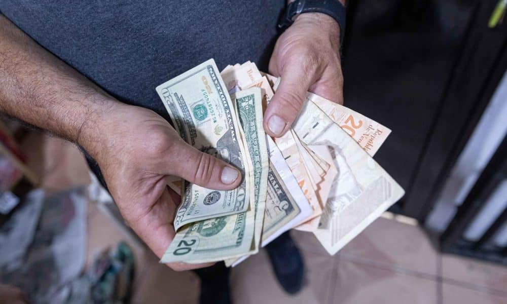 Fotografía de archivo de las manos de un hombre al contar dólares y bolívares de distintas denominaciones, en Caracas (Venezuela). EFE/Ronald Peña
