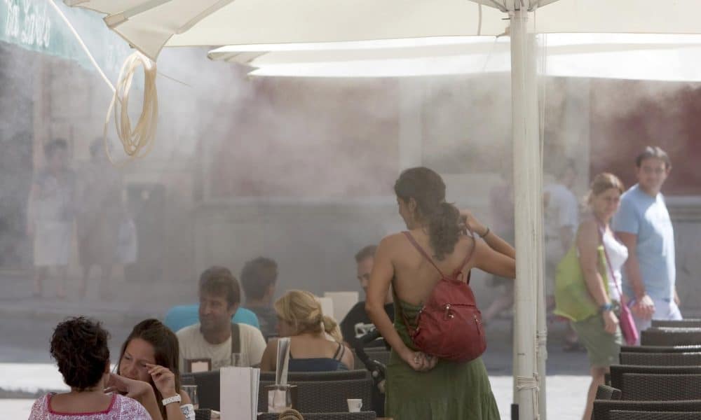 Unos turistas se refrescan en una terraza gracias a unas sombrillas equipadas con difusores de agua en la provincia de Sevilla, en una imagen de archivo. EFE/Julio Muñoz
