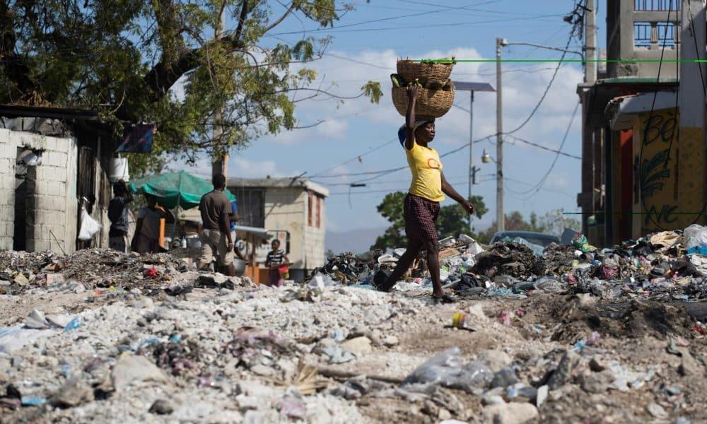 Fotografía de archivo de una mujer al caminar en medio de una calle cubierta por escombros y basura, tras una violentan protesta antigubernamental, en el populoso barrio Bell-Air, en Puerto Príncipe (Haití). EFE/ Orlando Barría