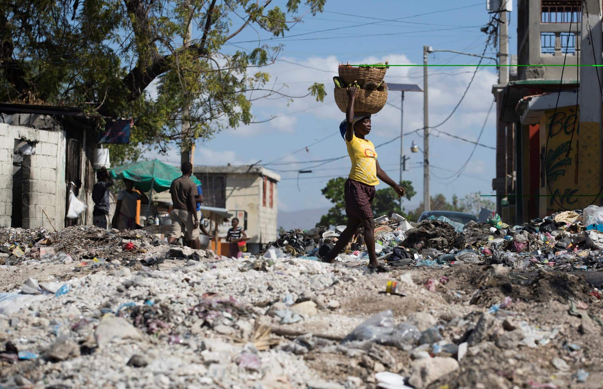 Fotografía de archivo de una mujer al caminar en medio de una calle cubierta por escombros y basura, tras una violentan protesta antigubernamental, en el populoso barrio Bell-Air, en Puerto Príncipe (Haití). EFE/ Orlando Barría