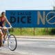 Fotografía de archivo de un par de jóvenes sobre una bicicleta al pasar frente a un cartel de campaña contra el Dengue, en Alamar (Cuba). EFE/Orlando Barría