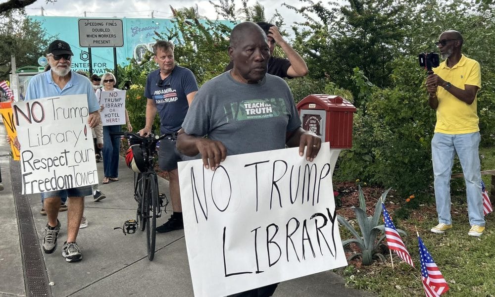 El historiador Marvin Dunn sostiene una pancarta en una protesta contra la futura biblioteca del presidente de los Estados Unidos, Donald Trump, este miércoles en Miami (Estados Unidos). EFE/ Blanca Escriche