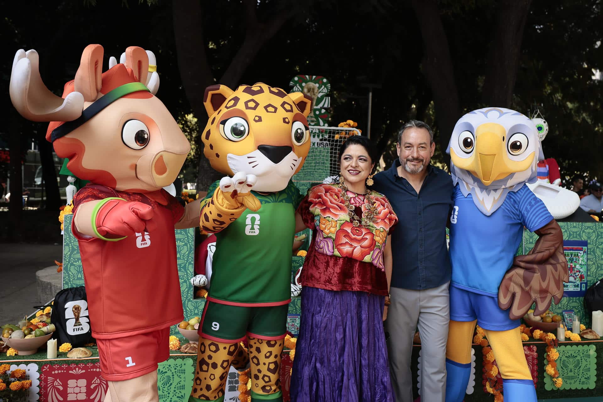 La secretaria de Cultura de la Ciudad de México, Alejandra Fraustro (3-i), y el oficial en jefe de torneo para México del Mundial 2026, Jurgen Mainka, posan junto a las mascotas oficiales del Mundial 2026 durante la inauguración de la Ofrenda FIFA este sábado, durante las festividades del Día de Muertos, en Ciudad de México (México). EFE/ José Méndez