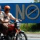 Fotografía de archivo en la que se captó a un par de ciudadanos al pasar en un motocicleta frente a un cartel de una campaña contra el dengue en Alamar (Cuba). EFE/Orlando Barría
