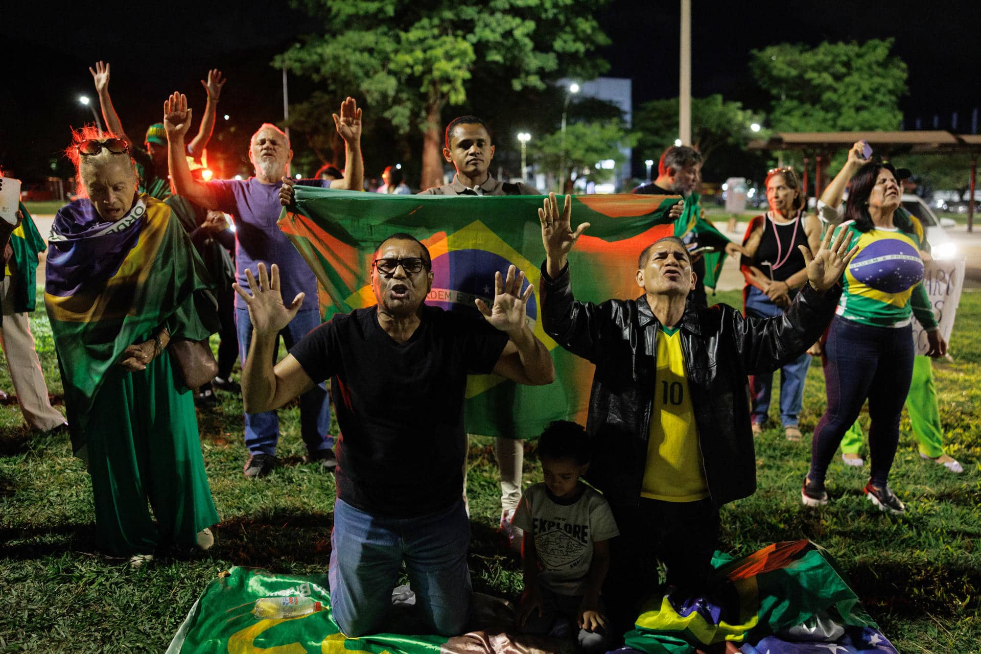 Simpatizantes del expresidente de Brasil, Jair Bolsonaro, rezan frente a la sede de la Policía Federal donde el exmandatario permanece detenido este sábado, en Brasilia (Brasil).. EFE/ Isaac Fontana