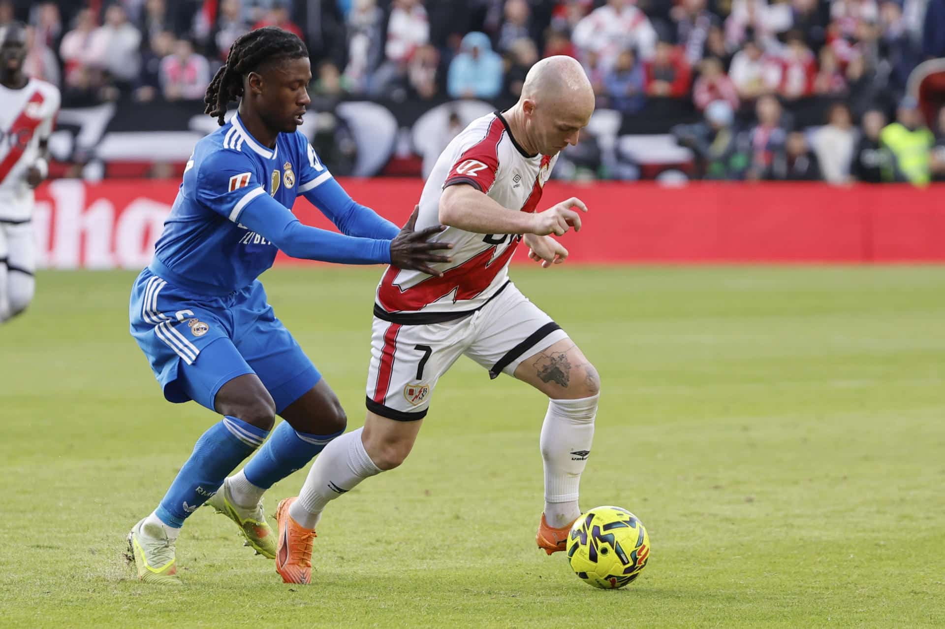 El centrocampista del Rayo Vallecano Isi Palazón (d) pelea un balón ante el centrocampista francés del Real Madrid Eduardo Camavinga durante el partido de la jornada 12 de LaLiga EA Sports que Rayo Vallecano y Real Madrid disputaron en el Estadio de Vallecas, en la capital española. EFE/ Sergio Pérez