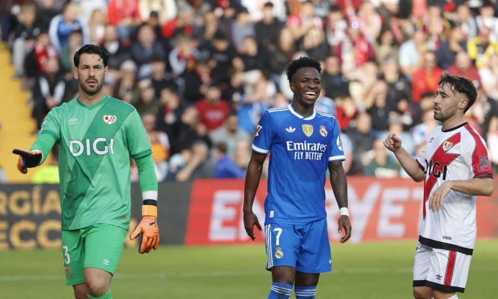 El delantero del Real Madrid Vinicius Jr (c) sonríe junto a Augusto Batalla (i) y Unai López (d), del Rayo Vallecano, durante el partido de la jornada 12 de LaLiga EA Sports que Rayo Vallecano y Real Madrid disputan este domingo en el Estadio de Vallecas, en la capital española. EFE/Mariscal