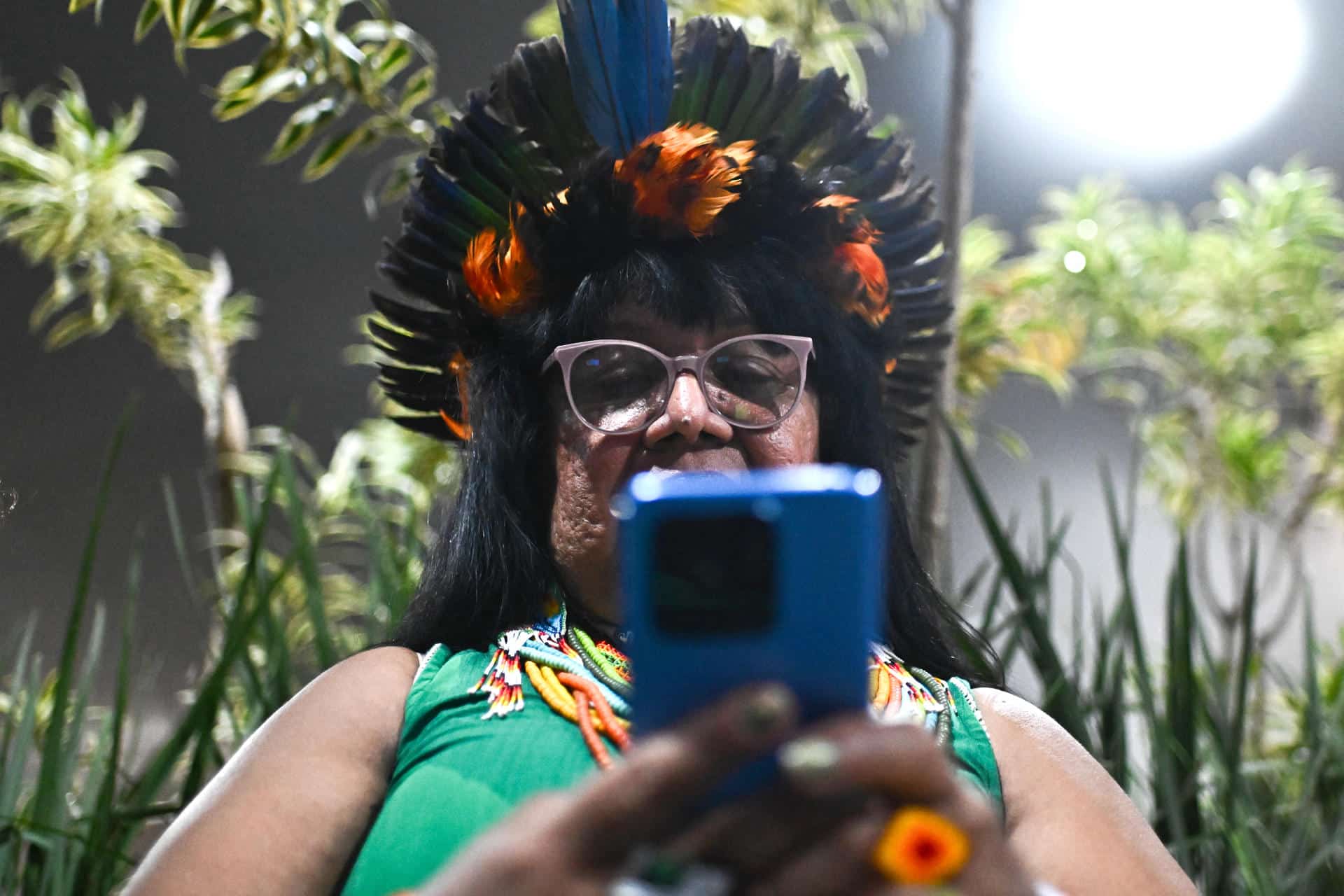 Una mujer indígena fue captada este miércoles, 12 de noviembre, al usar su teléfono móvil, en el Centro de Convenciones Hangar donde se realiza la COP30, en Belém (Brasil). EFE/Andre Borges