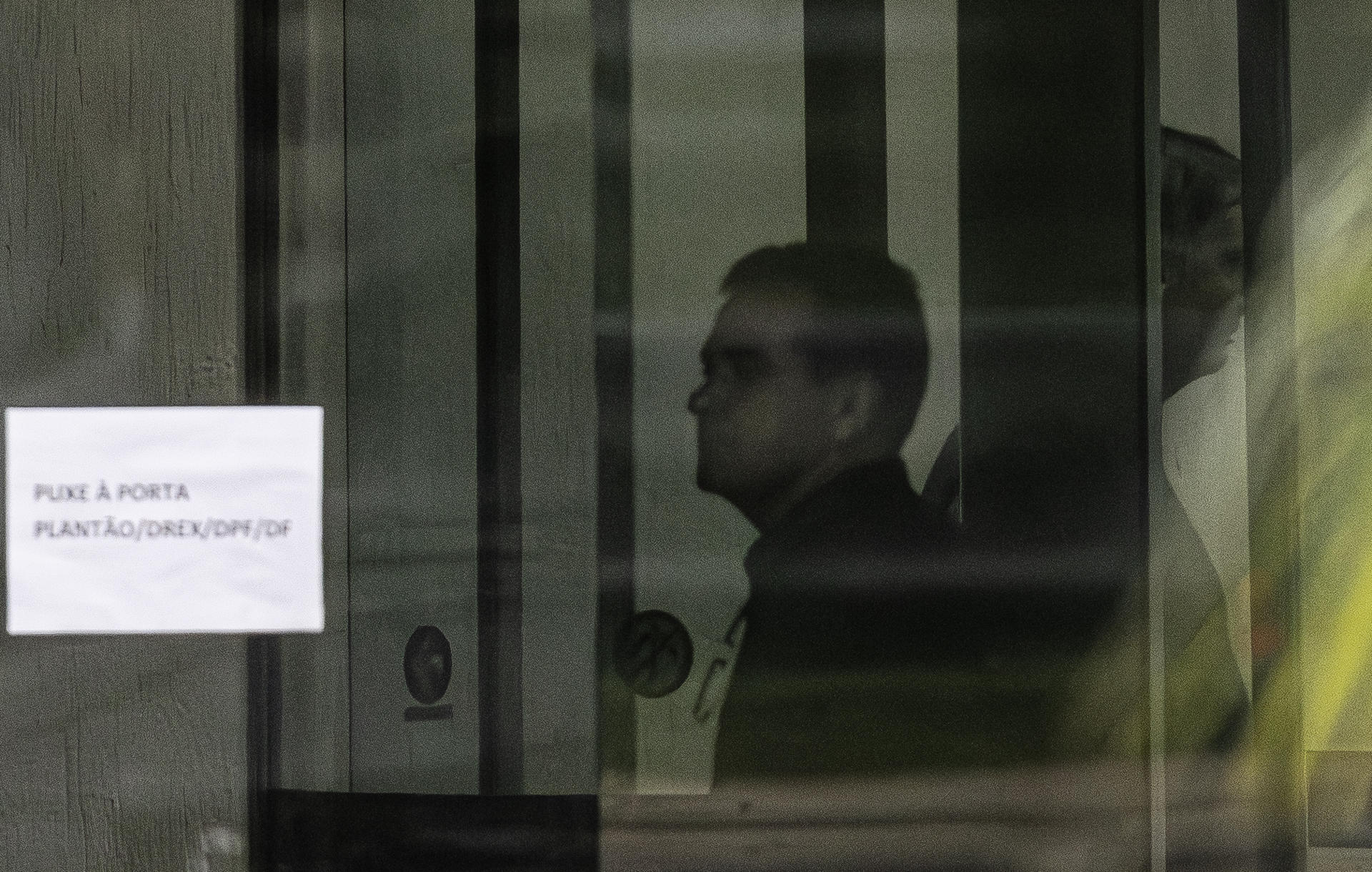Fotografía del 23 de noviembre de 2025 que muestra al expresidente de Brasil Jair Bolsonaro (d) detrás de una puerta de vidrio, en la Superintendencia de la Policía Federal en Brasilia (Brasil). EFE/ Isaac Fontana