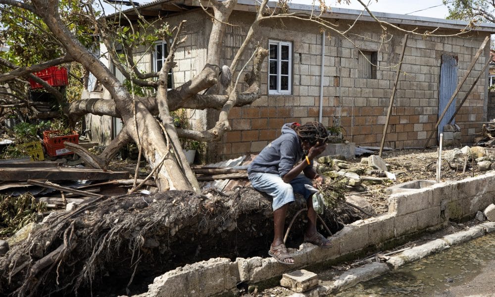 Un joven descansa frente a una casa llena de escombros tras el paso del huracán Melissa este lunes, en Falmouth (Jamaica) en una imagen reciente. EFE/Orlando Barría