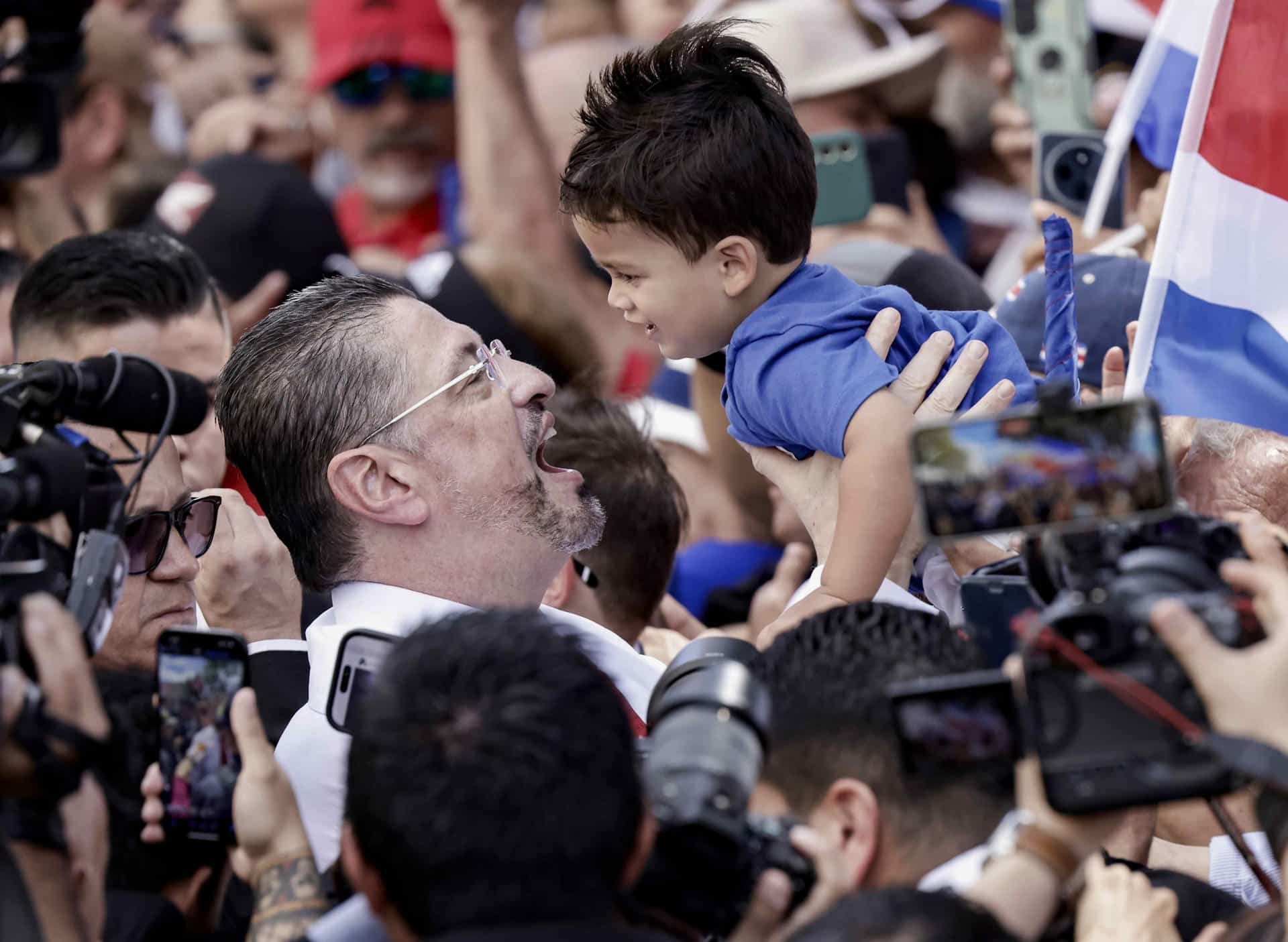El presidente de Costa Rica, Rodrigo Chaves, alza a un niño luego de una audiencia este viernes, en el exterior del Congreso en San José (Costa Rica). Chaves arengó a sus seguidores y cantó con ellos 'Llegó papá', tras la audiencia en una comisión legislativa que estudia una solicitud de desafuero presentada por el Tribunal Supremo de Elecciones (TSE) que le acusa de intervenir en temas electorales y políticos. EFE/ Jeffrey Arguedas