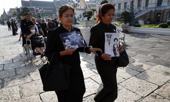 Dos mujeres tailandesas con retratos de la reina madre Sirikit y su esposo, el fallecido rey Bhumibol Adulyadej, hacen fila para rendir homenaje a la difunta en el Salón del Trono Dusit Maha Prasat dentro del Gran Palacio en Bangkok, Tailandia, el 9 de noviembre de 2025. EFE/EPA/RUNGROJ YONGRIT