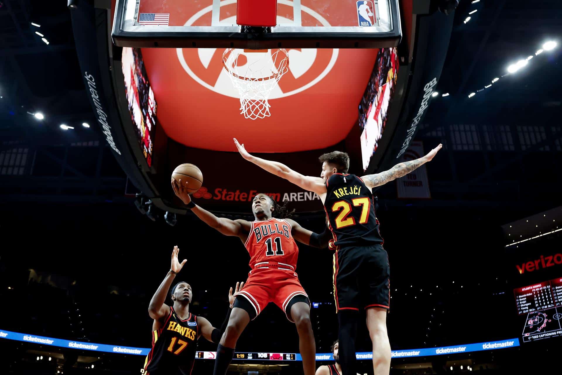El escolta de los Chicago Bulls Ayo Dosunmu (C) en acción contra el ala-pívot de los Atlanta Hawks Onyeka Okongwu (L) y el base Vit Krejci (R) durante la segunda mitad de un partido de baloncesto de la NBA en Atlanta, Georgia, EE.UU. EFE/EPA/ERIK S. LESSER