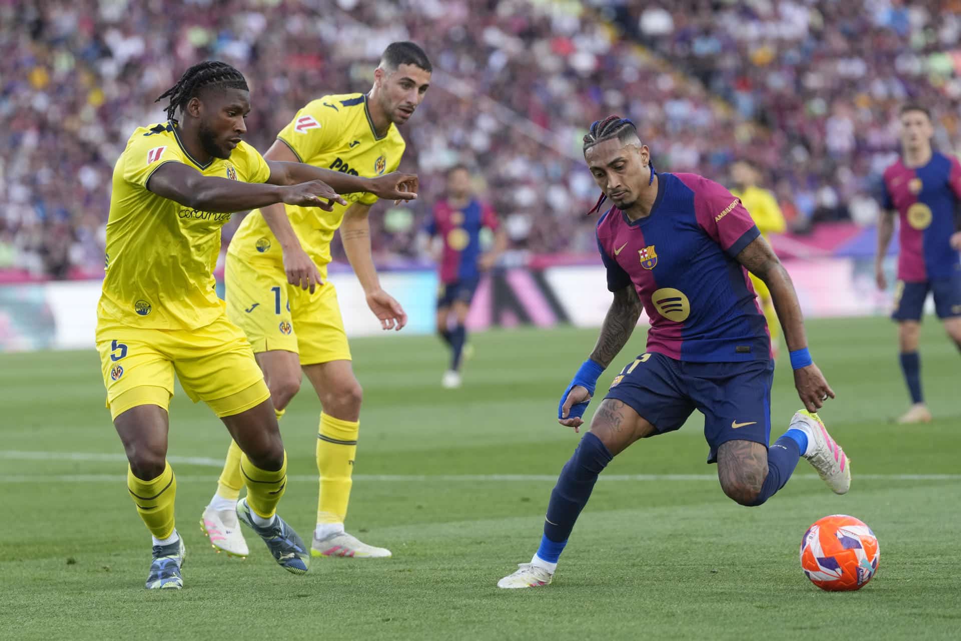 El delantero brasileño del Barcelona Raphinha (d) controla el balón ante dos jugaedores del Villarreal. EFE/ Enric Fontcuberta