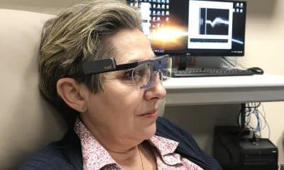 Berna_Spikes: Imagen de una paciente ciega, con una gafas para el seguimiento de su mirada y el registro de su actividad cerebral en el fondo. Cedida por el Instituto de Bioingeniería de la Universidad Miguel Hernández de Elche.