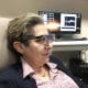 Berna_Spikes: Imagen de una paciente ciega, con una gafas para el seguimiento de su mirada y el registro de su actividad cerebral en el fondo. Cedida por el Instituto de Bioingeniería de la Universidad Miguel Hernández de Elche.