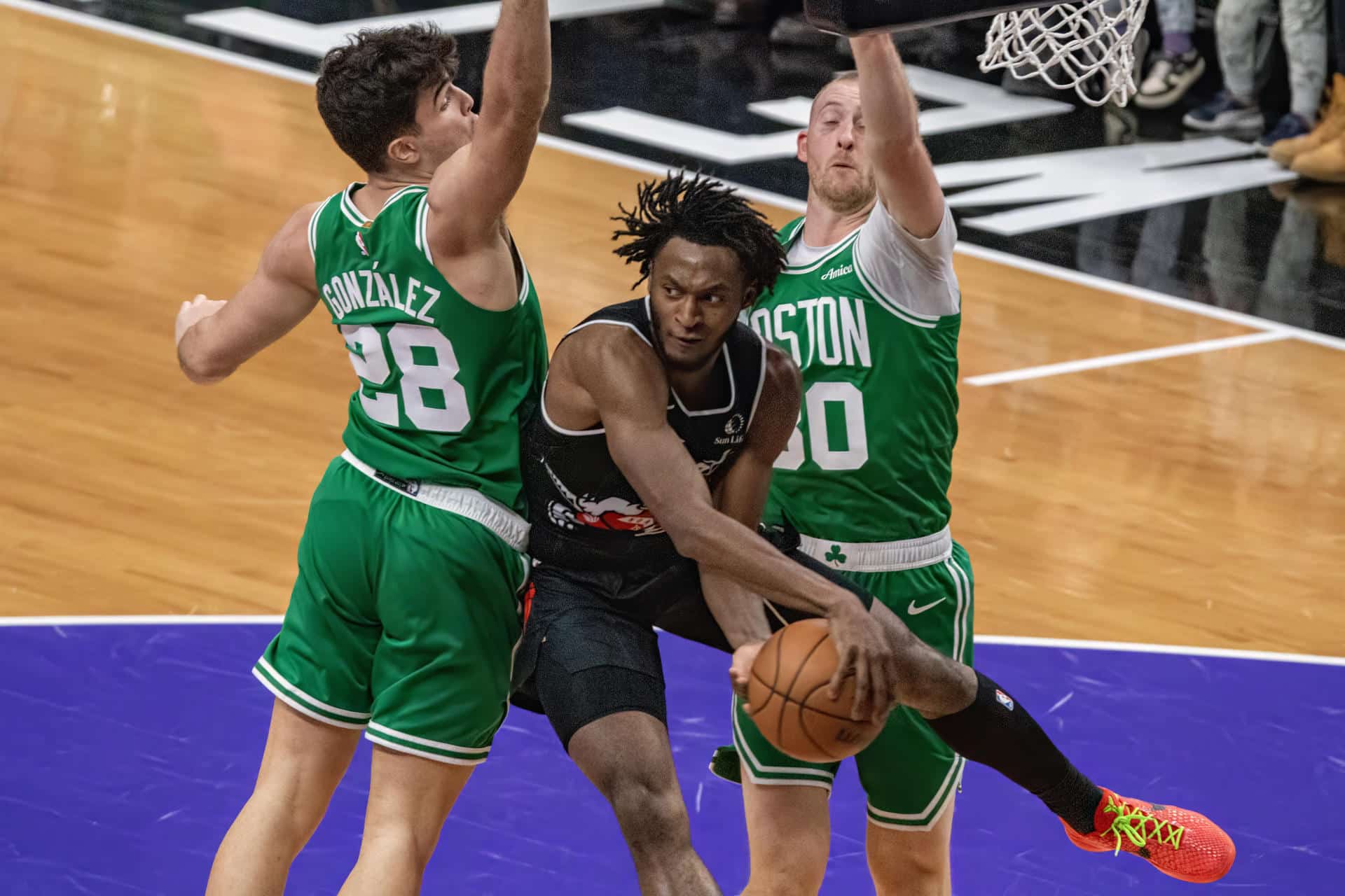 Immanuel Quickley (c), de Toronto Raptors, disputa el balón con Hugo González (i) de Boston Celtics este domingo durante un partido jugado en el Scotiabank Arena en Toronto. EFE/ Julio César Rivas