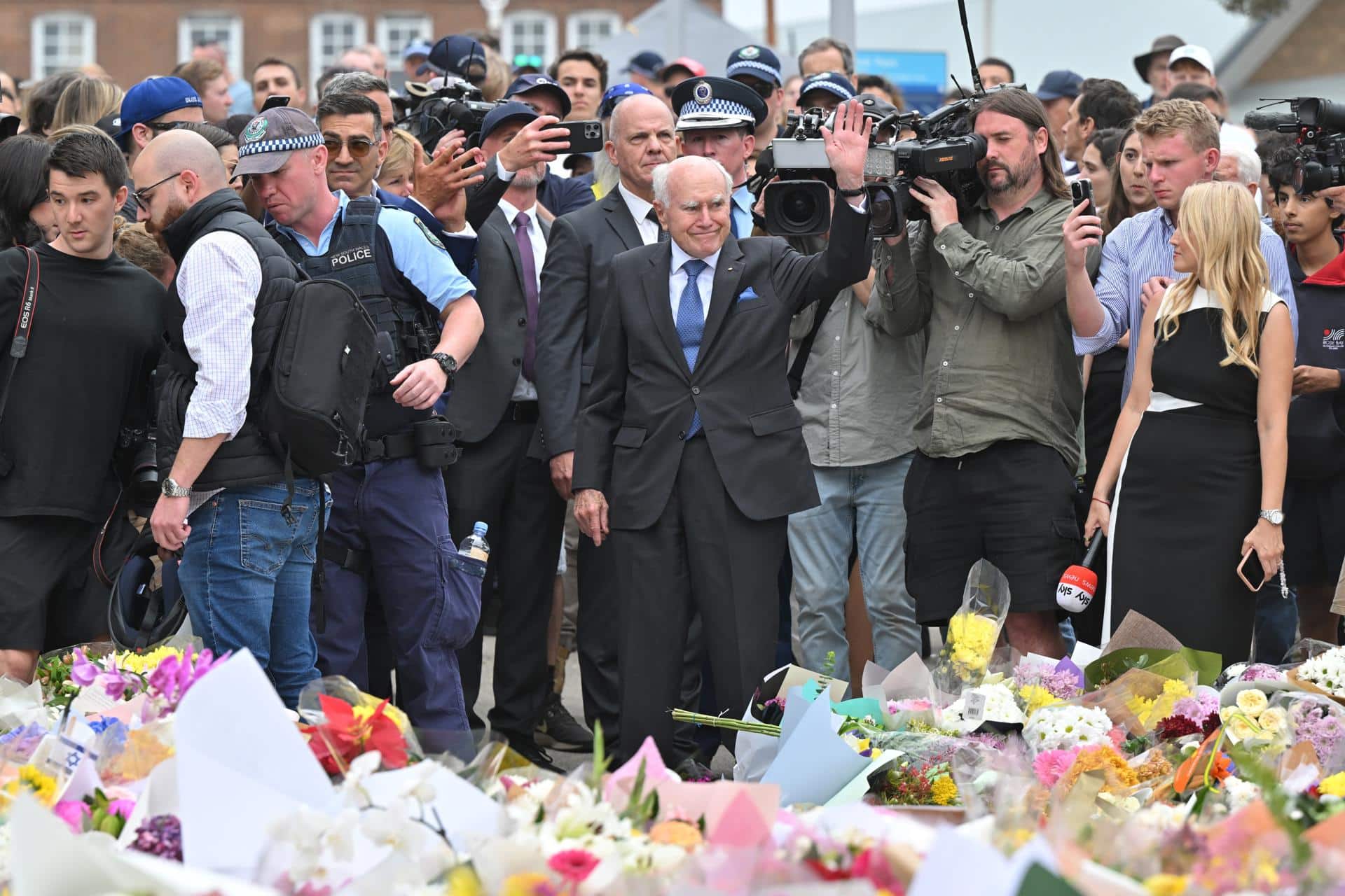 SYDNEY (Australia), 16/12/2025.- Former Australian Prime Minister John Howard (C) waves after placing flowers at a makeshift memorial at Bondi Beach in Sydney, Australia, 16 December 2025. Australia is in mourning following an attack on the Jewish community's Hanukkah festival celebrations on 14 December that left at least 16 people dead, including one gunman. EFE/EPA/MICK TSIKAS AUSTRALIA AND NEW ZEALAND OUT