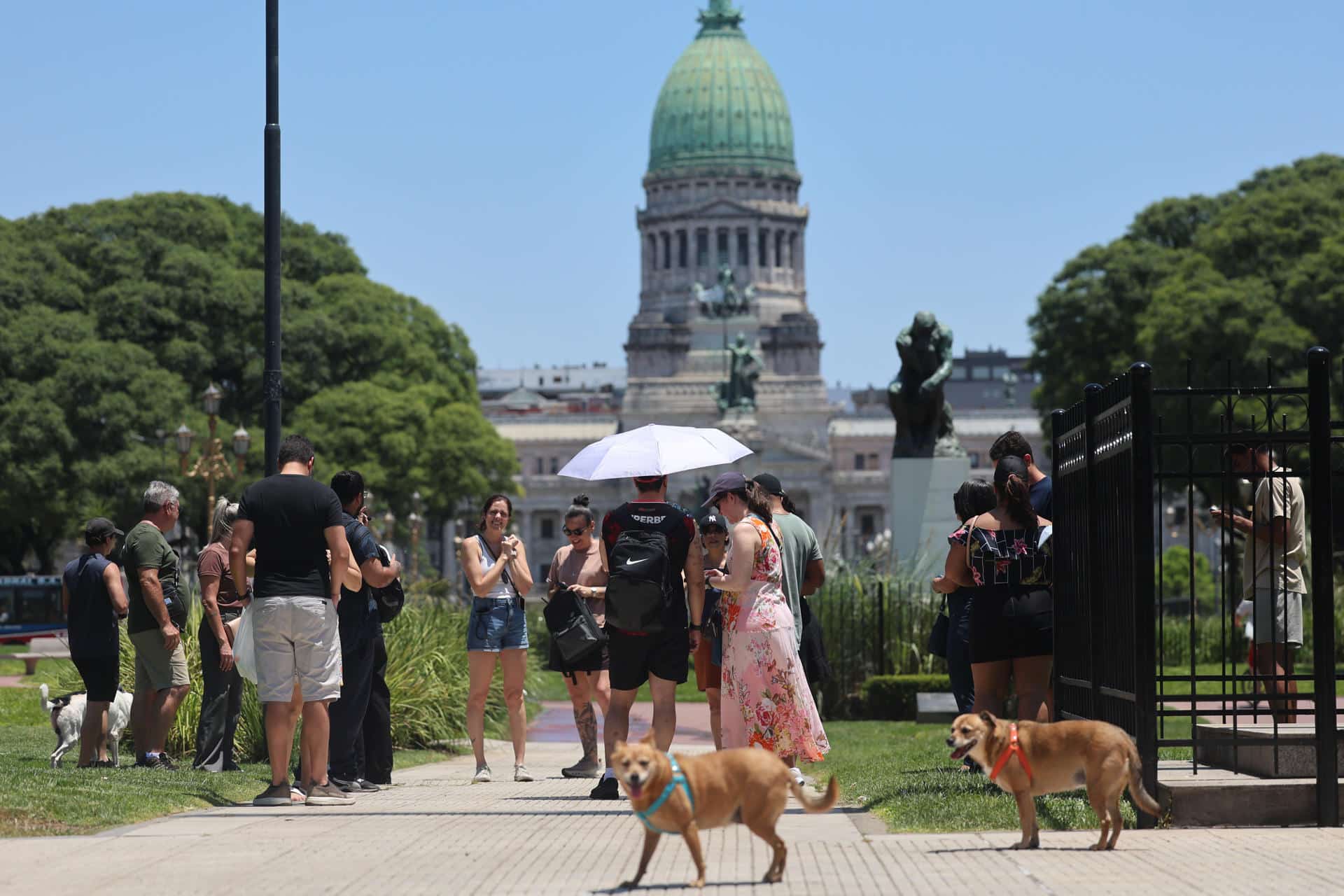 Personas caminan y se protegen del sol este martes, frente al Congreso en Buenos Aires (Argentina). EFE/ Juan Ignacio Roncoroni