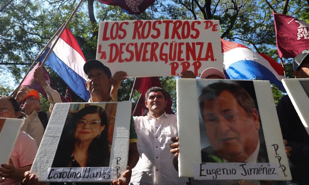 Personas sostiene carteles con la imagen de los ministros de la Corte Suprema de Justicia Carolina LLanes (i) y Eugenio Jiménez durante una manifestación este lunes, en Asunción (Paraguay). EFE/ Juan Pablo Pino