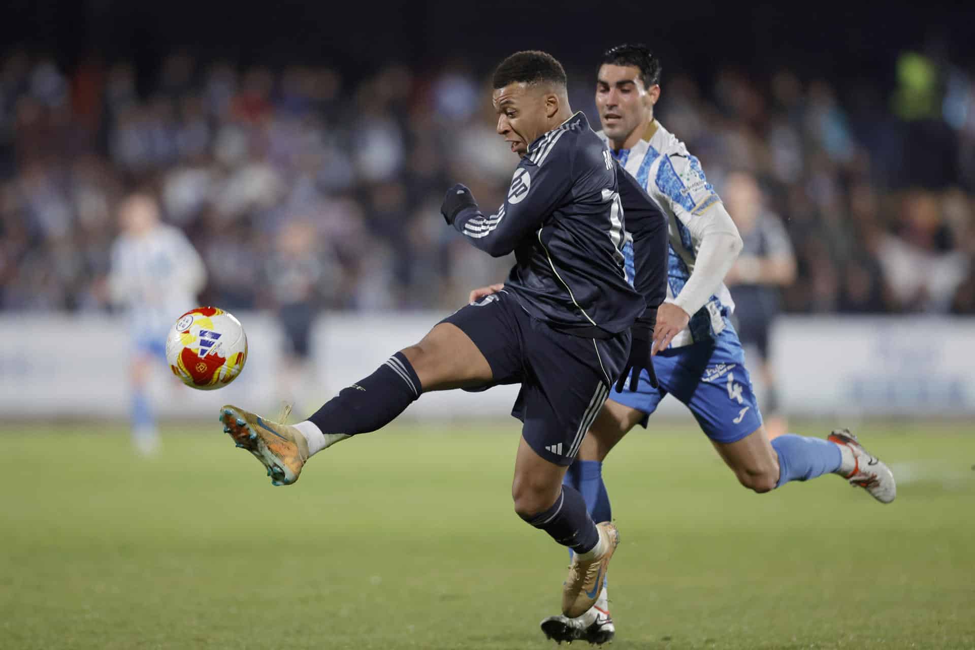El delantero francés del Real Madrid, Kylian Mbappé, golpea el balón ante el jugador del Talavera, Álvaro López, durante el partido de dieciseisavos de final de la Copa del Rey que Talavera CF y Real Madrid disputaron en el estadio de El Prado. EFE/Manu Reino