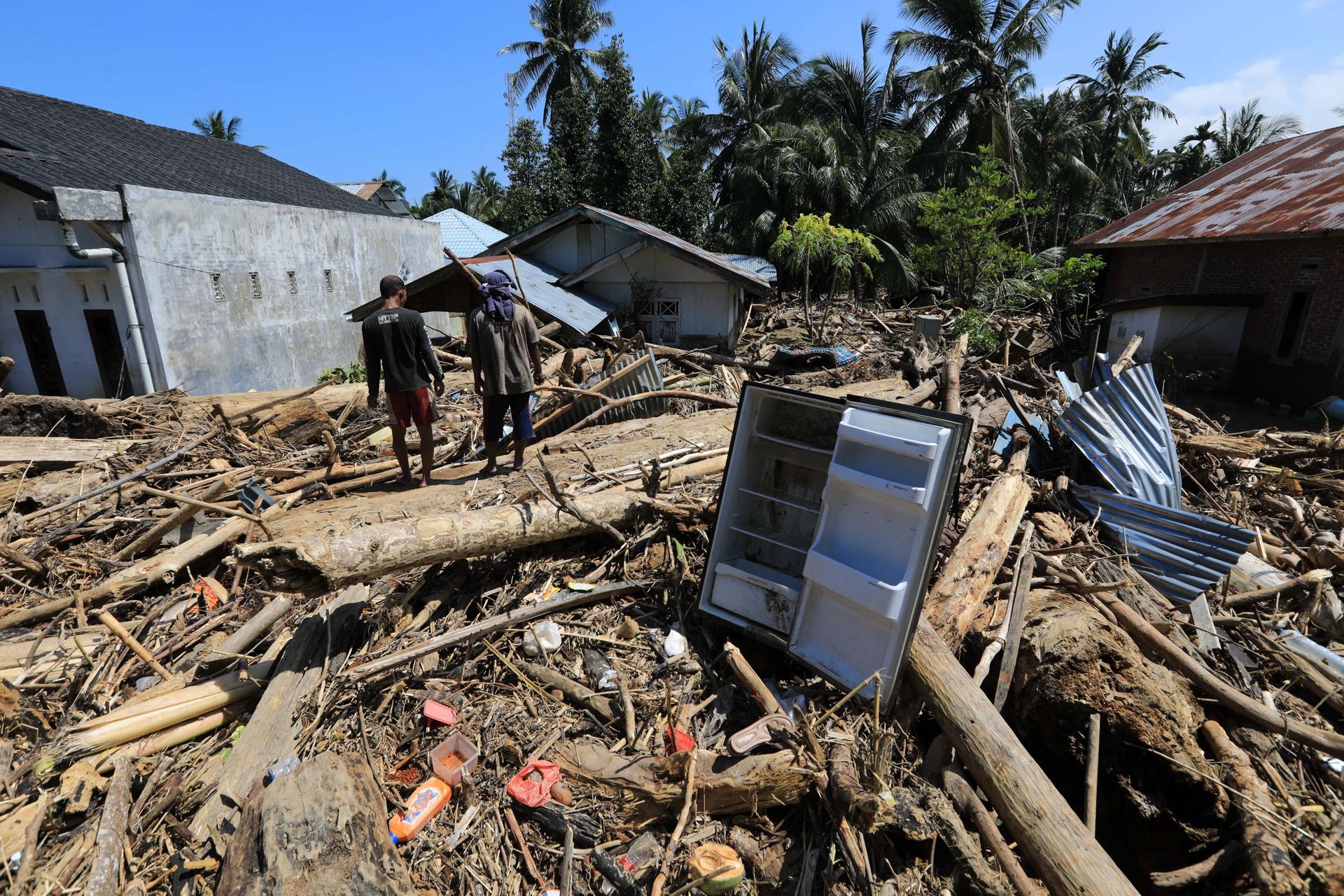 MEURUDU (Indonesia), 01/12/2025.- Residents walk among large piles of wood that were swept away by the floodwaters in a flood-affected village in the Meureudu area, Pidie Jaya Aceh, Indonesia, 01 December 2025. According to National Disaster Management Agency Floods and landslides triggered by Tropical Cyclone Senyar have killed at least 442 people across Aceh, North Sumatra, and West Sumatra provinces. This number is expected to rise, as approximately 402 people remain uncounted for. (Inundaciones) EFE/EPA/HOTLI SIMANJUNTAK