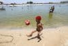 Un niño juega con un balón en la playa del lago artificial 'Piscinão de Ramos' este viernes, en Río de Janeiro (Brasil). EFE/ Antonio Lacerda
