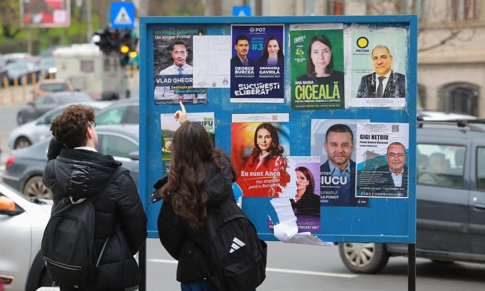 Una joven pareja rumana se detiene a comentar frente a un cartel que muestra los carteles de campaña de los candidatos a alcalde de la capital rumana, en el centro de Bucarest, Rumanía, 5 de diciembre de 2025. 
 EFE/EPA/ROBERT GHEMENT