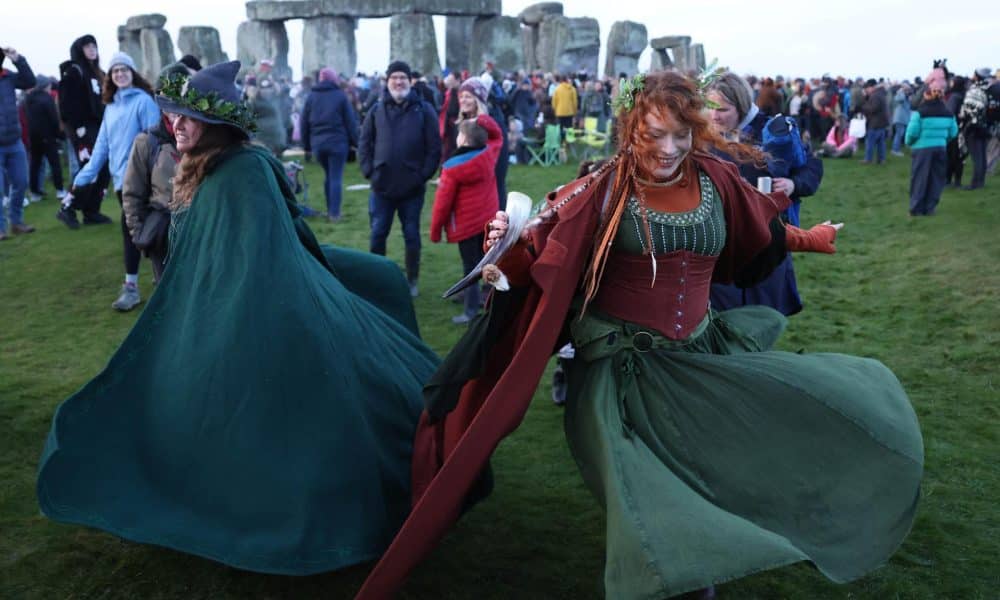 Dos mujeres bailan este domingo ante el monumento megalítico de Stonehenge, cerca de Amesbury (Reino Unido), para celebrar el solsticio de invierno, el día más corto del año en el hemisferio norte. EFE/EPA/NEIL HALL