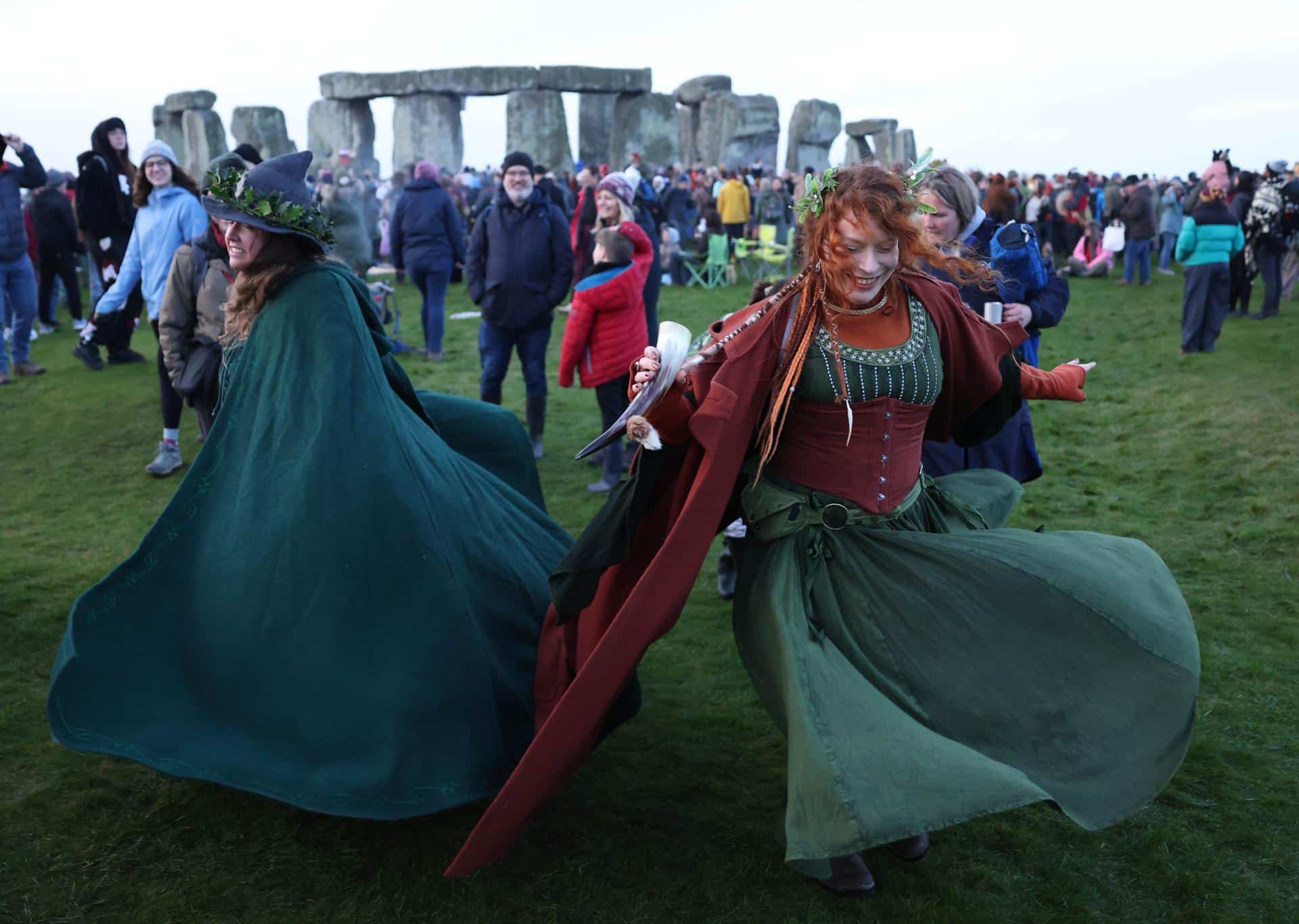 Dos mujeres bailan este domingo ante el monumento megalítico de Stonehenge, cerca de Amesbury (Reino Unido), para celebrar el solsticio de invierno, el día más corto del año en el hemisferio norte. EFE/EPA/NEIL HALL