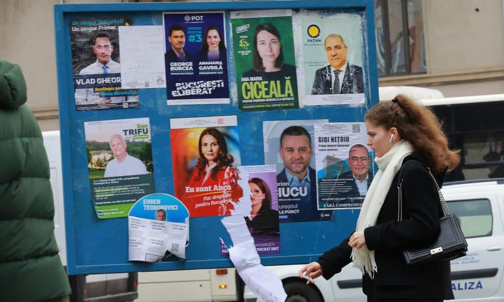 Una joven rumana pasa por un cartel que muestra los carteles de campaña de los candidatos a alcalde de la capital rumana, en el centro de Bucarest, Rumanía, 5 de diciembre de 2025. 
 EFE/EPA/ROBERT GHEMENT