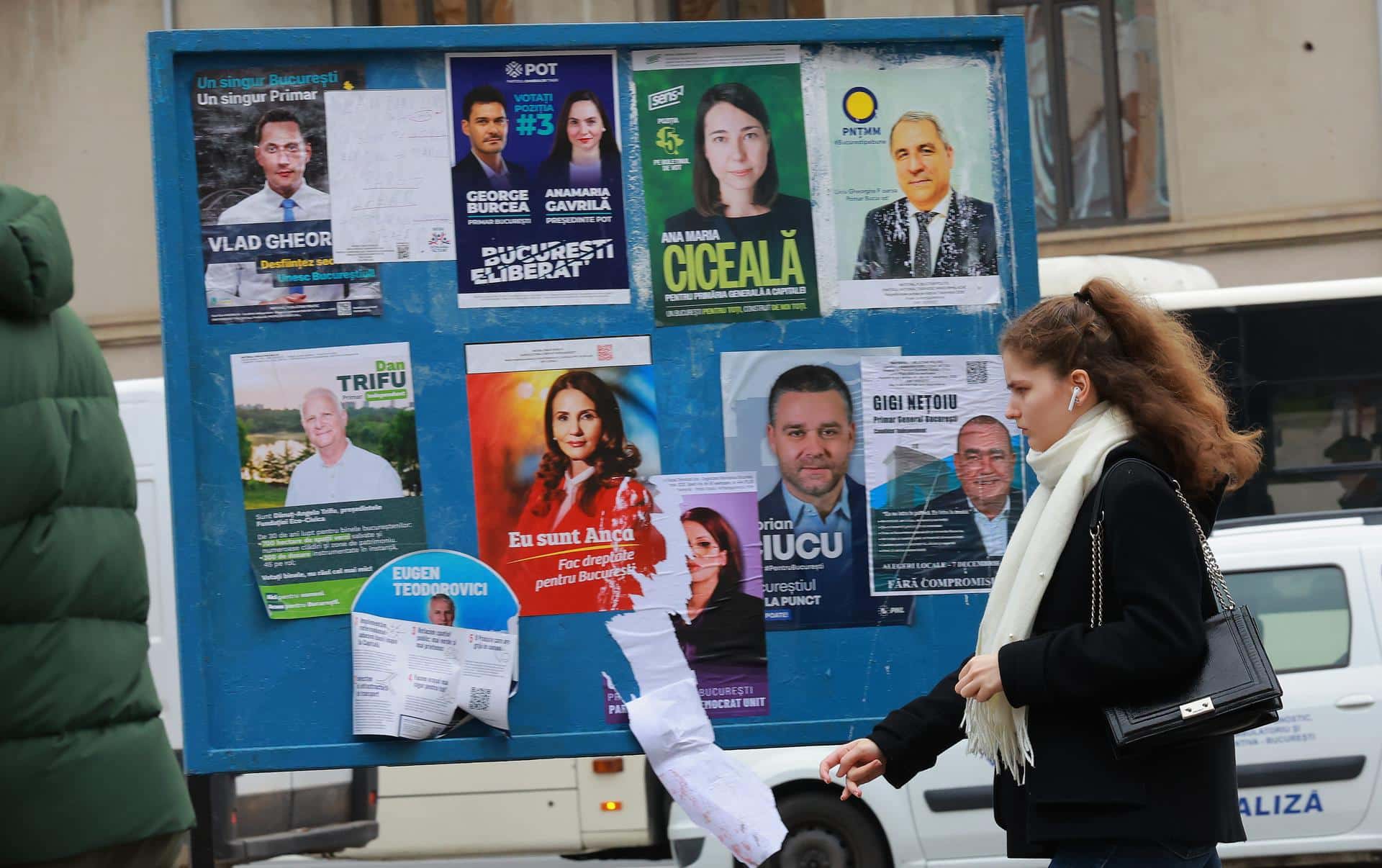 Una joven rumana pasa por un cartel que muestra los carteles de campaña de los candidatos a alcalde de la capital rumana, en el centro de Bucarest, Rumanía, 5 de diciembre de 2025. 
 EFE/EPA/ROBERT GHEMENT