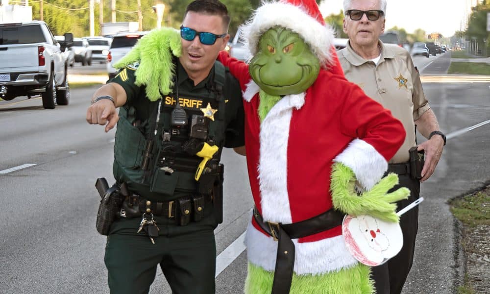 Fotografía cedida por la Oficina del Sheriff del Condado de Monroe que muestra al coronel retirado Lou Caputo, disfrazado del Grinch (d), abrasando al sargento, James Hager (i), mientras supervisan el tráfico este viernes, en la zona escolar de Cayo Largo, Florida, (EE.UU.). EFE/ Andy Newman/ Oficina Sheriff Del Condado Monroe /SOLO USO EDITORIAL/ NO VENTAS/ SOLO DISPONIBLE PARA ILUSTRAR LA NOTICIA QUE ACOMPAÑA (CRÉDITO OBLIGATORIO)