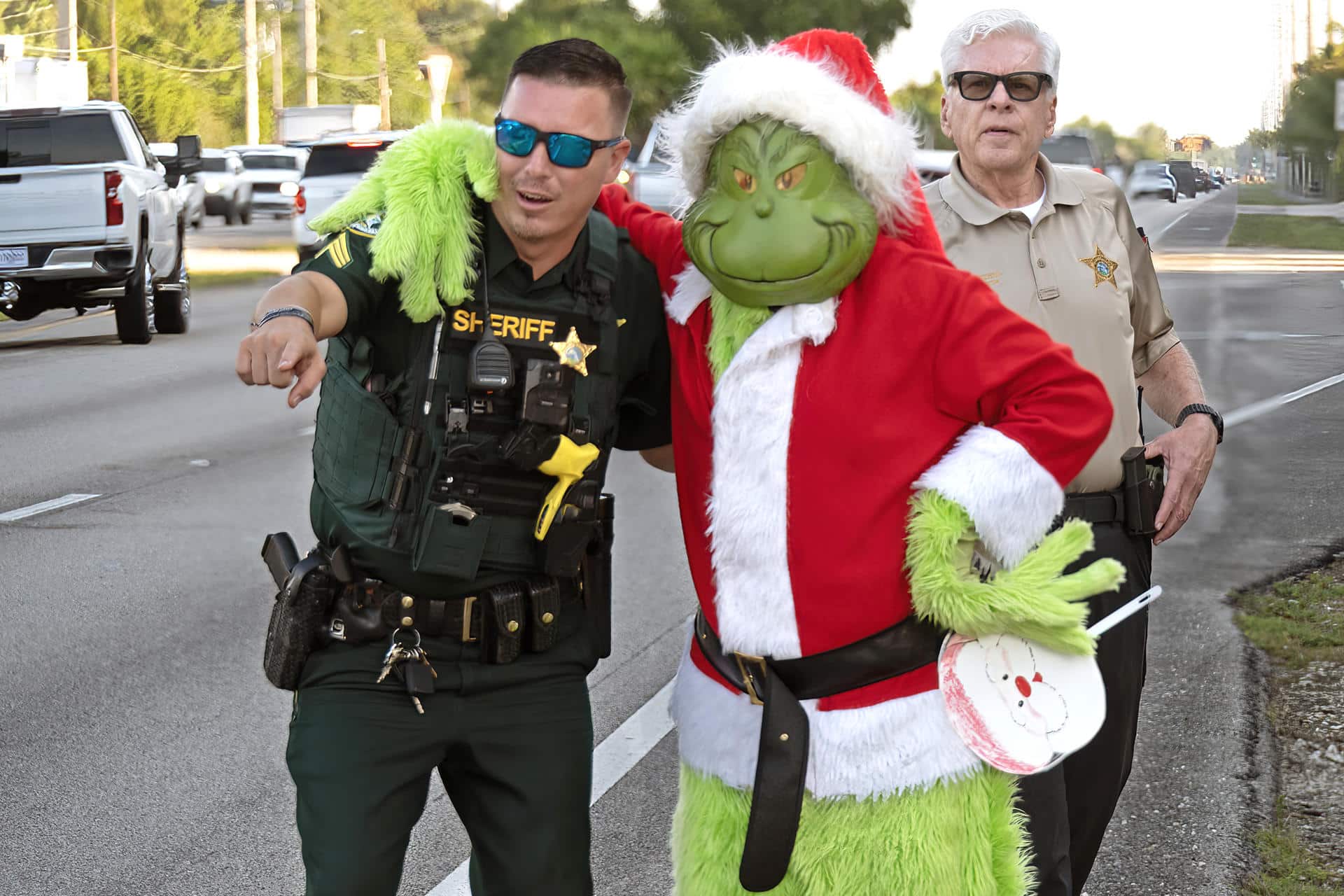 Fotografía cedida por la Oficina del Sheriff del Condado de Monroe que muestra al coronel retirado Lou Caputo, disfrazado del Grinch (d), abrasando al sargento, James Hager (i), mientras supervisan el tráfico este viernes, en la zona escolar de Cayo Largo, Florida, (EE.UU.). EFE/ Andy Newman/ Oficina Sheriff Del Condado Monroe /SOLO USO EDITORIAL/ NO VENTAS/ SOLO DISPONIBLE PARA ILUSTRAR LA NOTICIA QUE ACOMPAÑA (CRÉDITO OBLIGATORIO)
