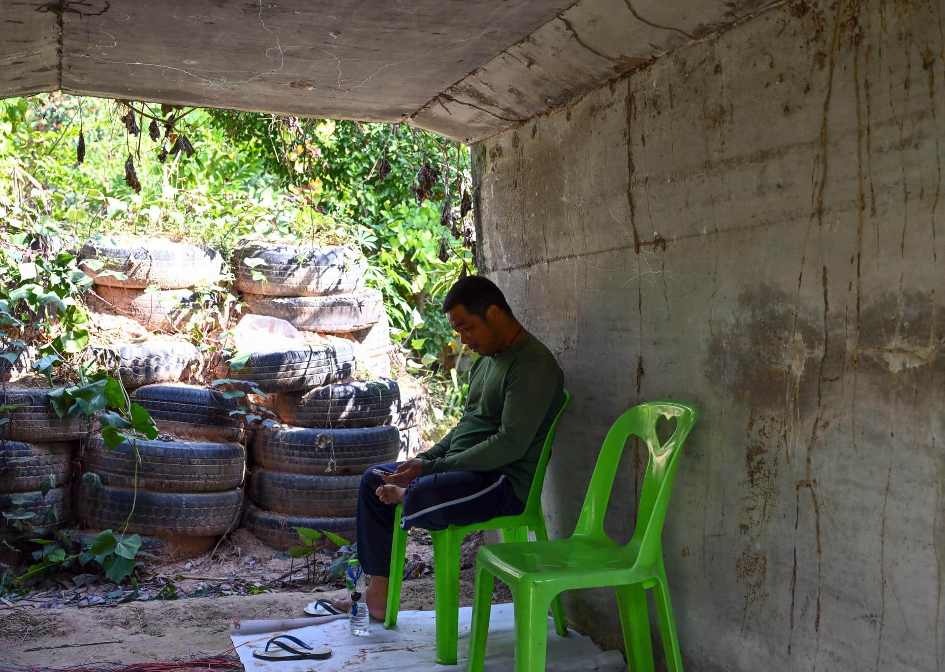 Dong Rak (Thailand), 08/12/2025.- A Thai villager monitors the situation via a mobile phone as he takes shelter under a concrete bunker following clashes between Thai and Cambodian troops in Phanom Dong Rak district, Surin province, Thailand, 08 December 2025.The Royal Thai Army has reported a Thai soldier was killed and other eight wounded in the multiple border area clashes between Thai and Cambodian troops after Cambodian troops attacked in the Phu Pha Lek hill of Phlan Hin Paet Kon area in Kantharalak district, Si Sa Ket province that prompted the evacuation of residents in four northeastern provinces bordering Cambodia, according to Thai Army spokesman Major General Winthai Suvaree. (Camboya, Tailandia) EFE/EPA/KAIKUNGWON DUANJUMROON
