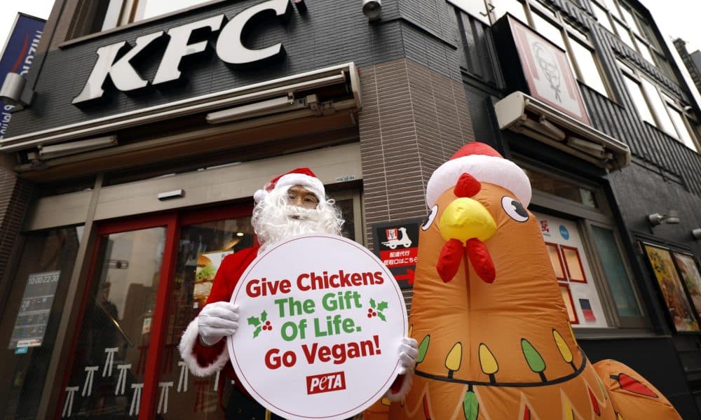TOKYO (Japan), 03/12/2025.- Wearing a Santa Claus costume, an animal rights activist of People for the Ethical Treatment of Animals (PETA) stands next to an inflatable chicken in front of a KFC fast food restaurant in Tokyo, Japan, 03 December 2025. In a statement, PETA said it is protesting against cruelty on chickens reported at a KFC supplier in Japan. (Protestas, Japón, Tokio) EFE/EPA/FRANCK ROBICHON