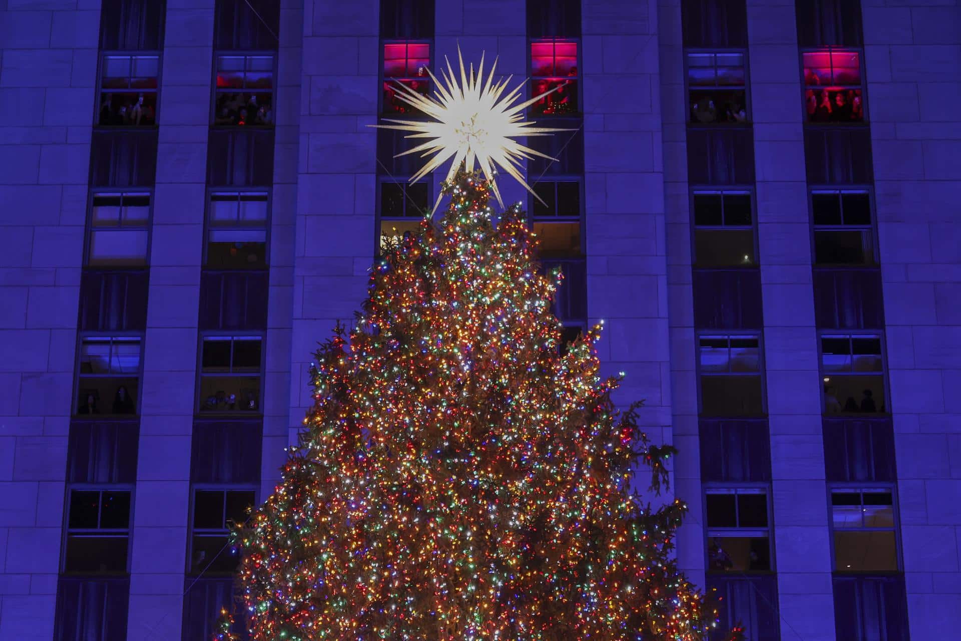 Personas dentro del edificio observan el árbol de Navidad del Rockefeller Center después de encenderse durante la ceremonia de iluminación en Nueva York, EE.UU., el 3 de diciembre de 2025. EFE/EPA/SARAH YENESEL