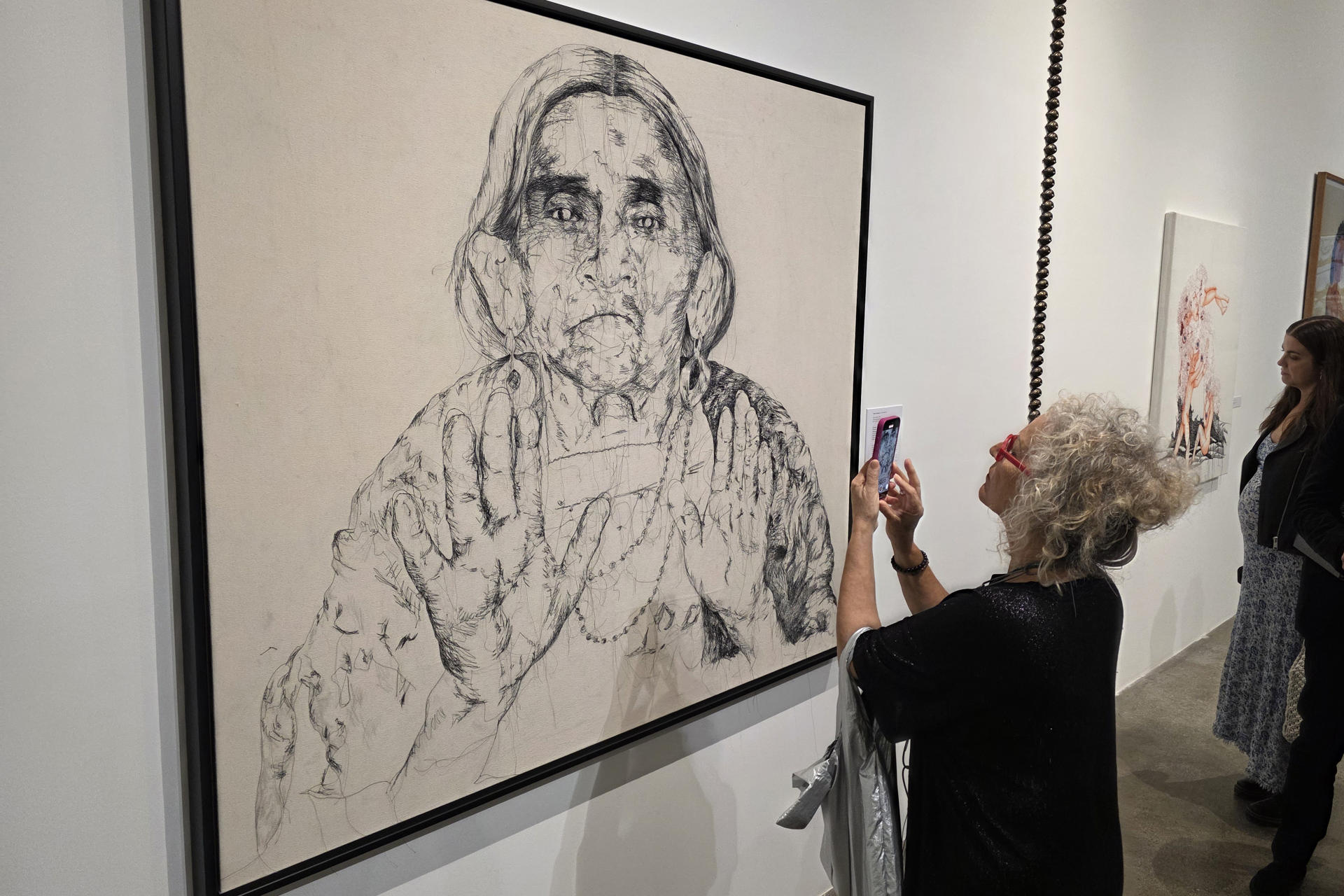 Una mujer toma una fotografía en una exposición este lunes, durante el 'Miami Art Week´ en Miami (Estados Unidos). Miami se transforma en un centro cultural del mundo con el comienzo de la Semana del Arte de Miami, en la que convergen cerca de 20 ferias artísticas y más de 1.200 galerías. EFE/ Alberto Boal