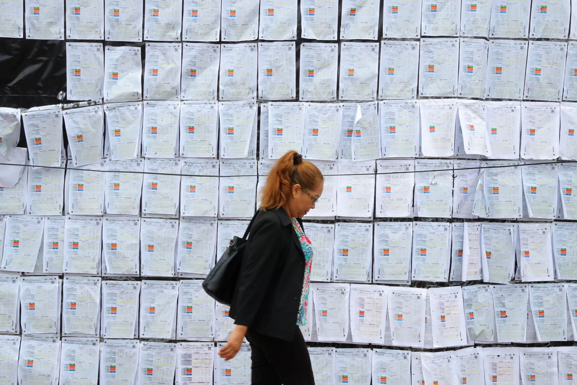 Fotografía del 26 de diciembre de 2025 que muestra a una mujer caminando frente a copias de actas electorales a las afueras del Centro Logístico Electoral (CLE) en Tegucigalpa (Honduras). EFE/ Gustavo Amador