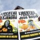 Personas sostienen carteles en apoyo a los activistas y líderes comunitarios Alejandro Henríquez y José Ángel Pérez en El Salvador. EFE/ Rodrigo Sura
