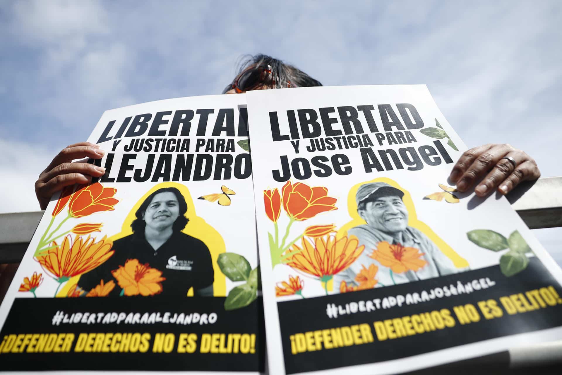 Personas sostienen carteles en apoyo a los activistas y líderes comunitarios Alejandro Henríquez y José Ángel Pérez en El Salvador. EFE/ Rodrigo Sura