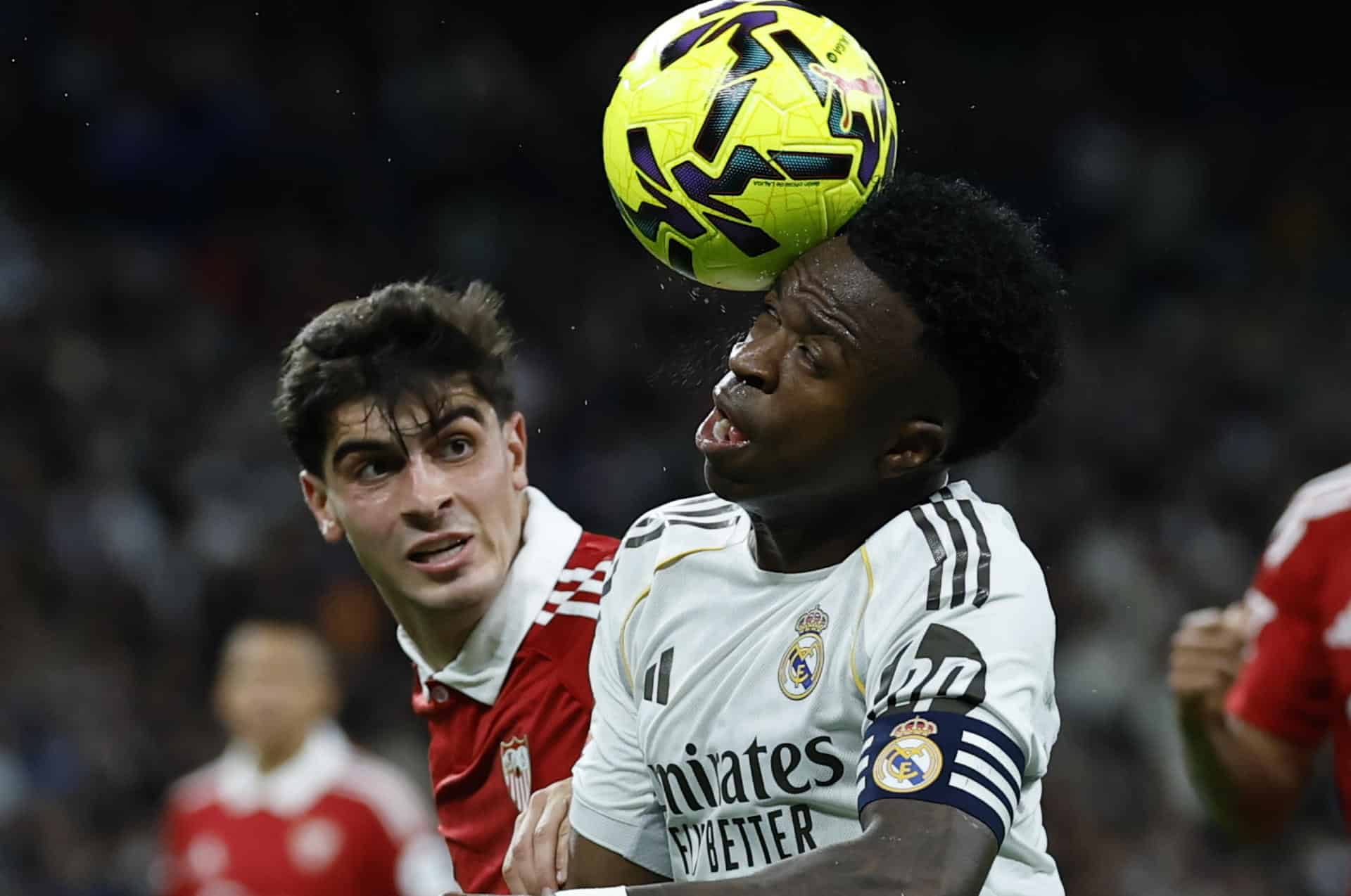 El delantero brasileño del Real Madrid, Vinicius Junior (d), controla el balón ante el defensa del Sevilla, Juanlu Sánchez, en el estadio Santiago Bernabéu, en Madrid. EFE / Juanjo Martín.