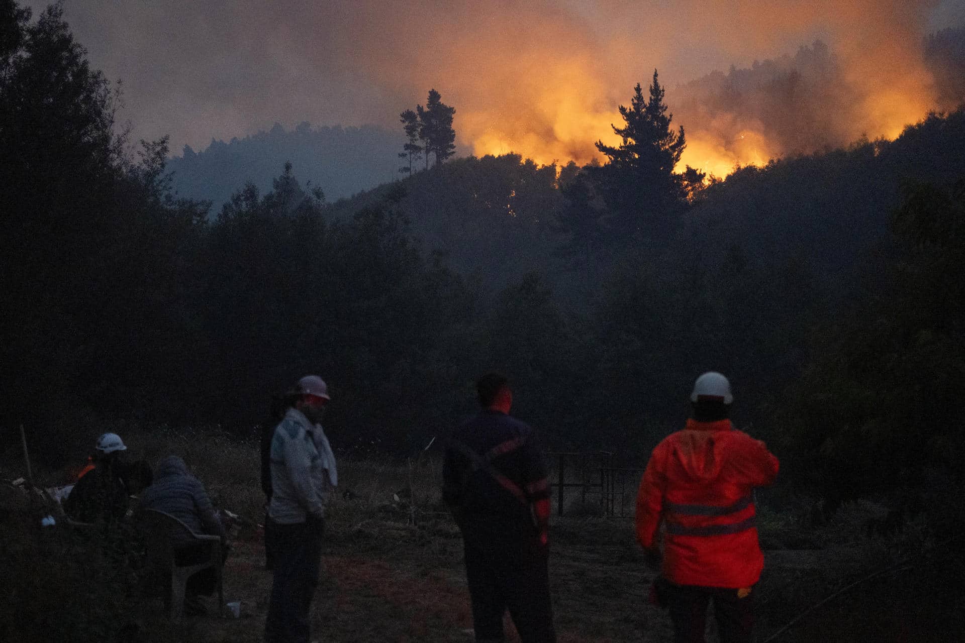 Personas observan un incendio forestal este lunes, en la comuna de Chaimávida, en Concepción a unos 491 km aproximadamente de Santiago (Chile). Los megaincendios originados el sábado pasado han destruido hasta ahora más de 30.000 hectáreas en las regiones de Biobío y Ñuble, a 400 y 500 kilómetros al sur de Santiago, respectivamente, y han obligado a evacuar decenas de miles de personas. EFE/ Adriana Thomasa