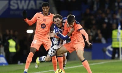 El defensa de la Real Álvaro Odriozola (c) cae entre Gerard Martín (d) y Marcus Rashford, ambos del Barcelona, durante el partido de LaLiga EA Sports que Real Sociedad y FC Barcelona han disputado en el estadio de Anoeta, en San Sebastián. EFE/Juan Herrero