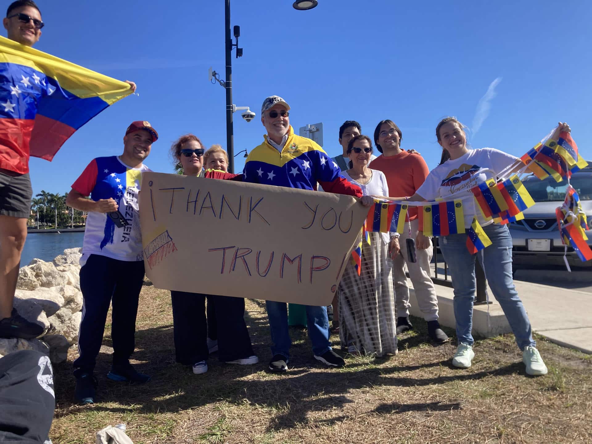Simpatizantes del presidente de Estados Unidos, Donald Trump, sostienen banderas y un cartel previo a una rueda de prensa del mandatario este sábado, en West Palm Beach (Estados Unidos). EFE/ Ivonne Malaver