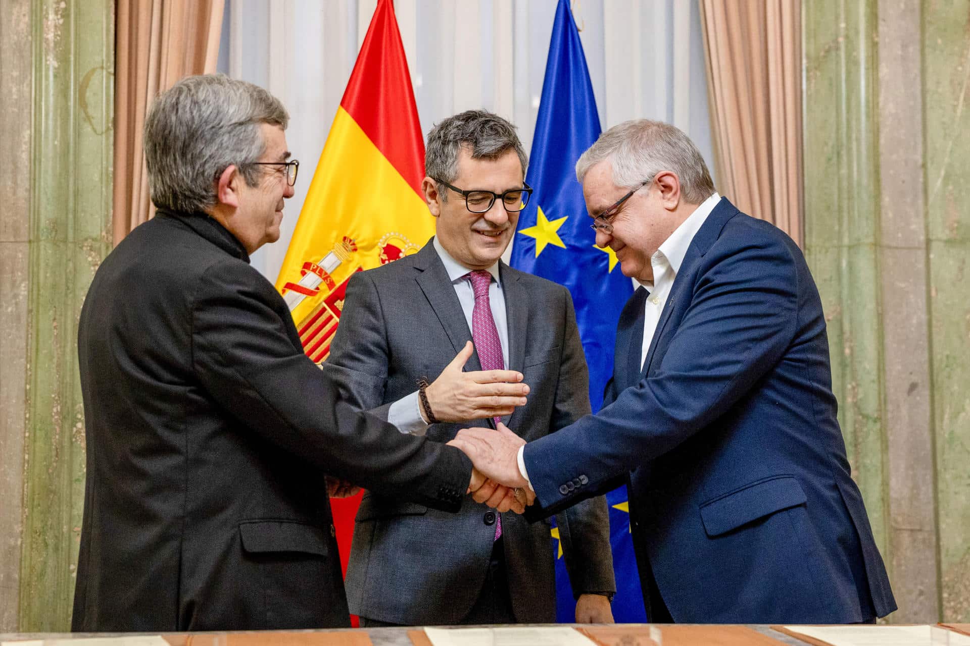 El ministro español de Justicia, Félix Bolaños (c), el presidente de la Conferencia Episcopal, Luis Argüello (i), y el presidente de la Conferencia Española de Religiosos (CONFER), Jesús Díaz Sariego (d), se saludan en la firma de un acuerdo para la reparación de víctimas de abusos sexuales cometidos en el seno de la Iglesia católica. EFE/ Daniel González