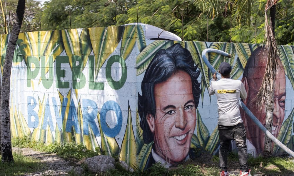 Una persona realiza labores de limpieza frente a un mural con los rostros de los artistas Julio Iglesias y Johnny Ventura en Punta Cana (República Dominicana). EFE/ Orlando Barría
